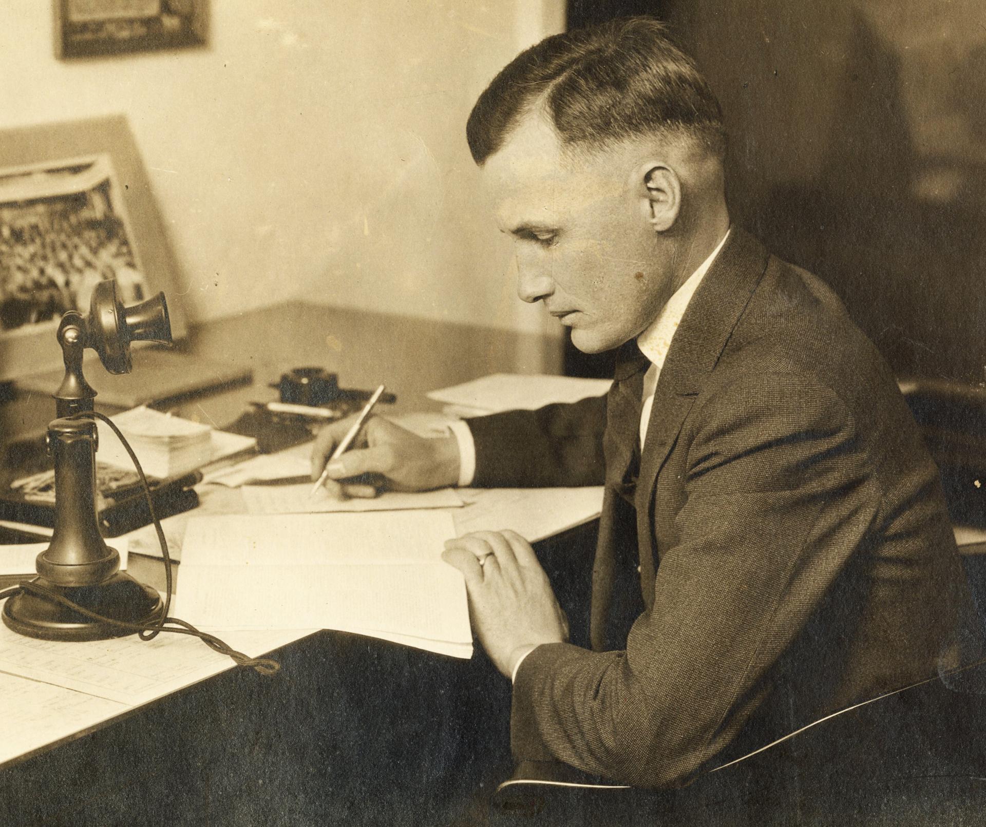 Antique photograph of a man writing intently at a desk